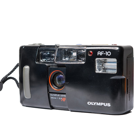 Film negativ pentru Olympus AF-10, expus pe suport alb, evidențiind detaliile și textura filmului fotografiilor analogice.